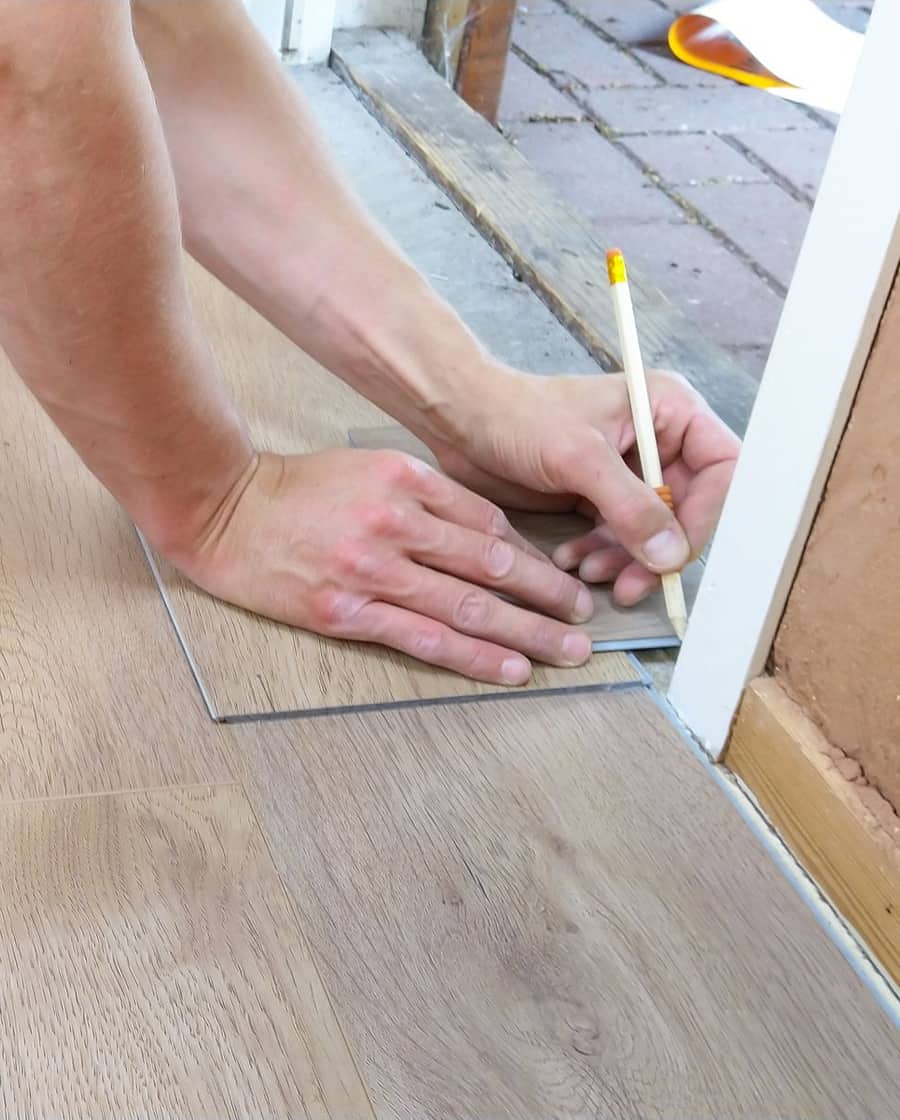 Hände zeichnen mit einem Bleistift eine Diele an einer Türzarge an. Beispielfoto.