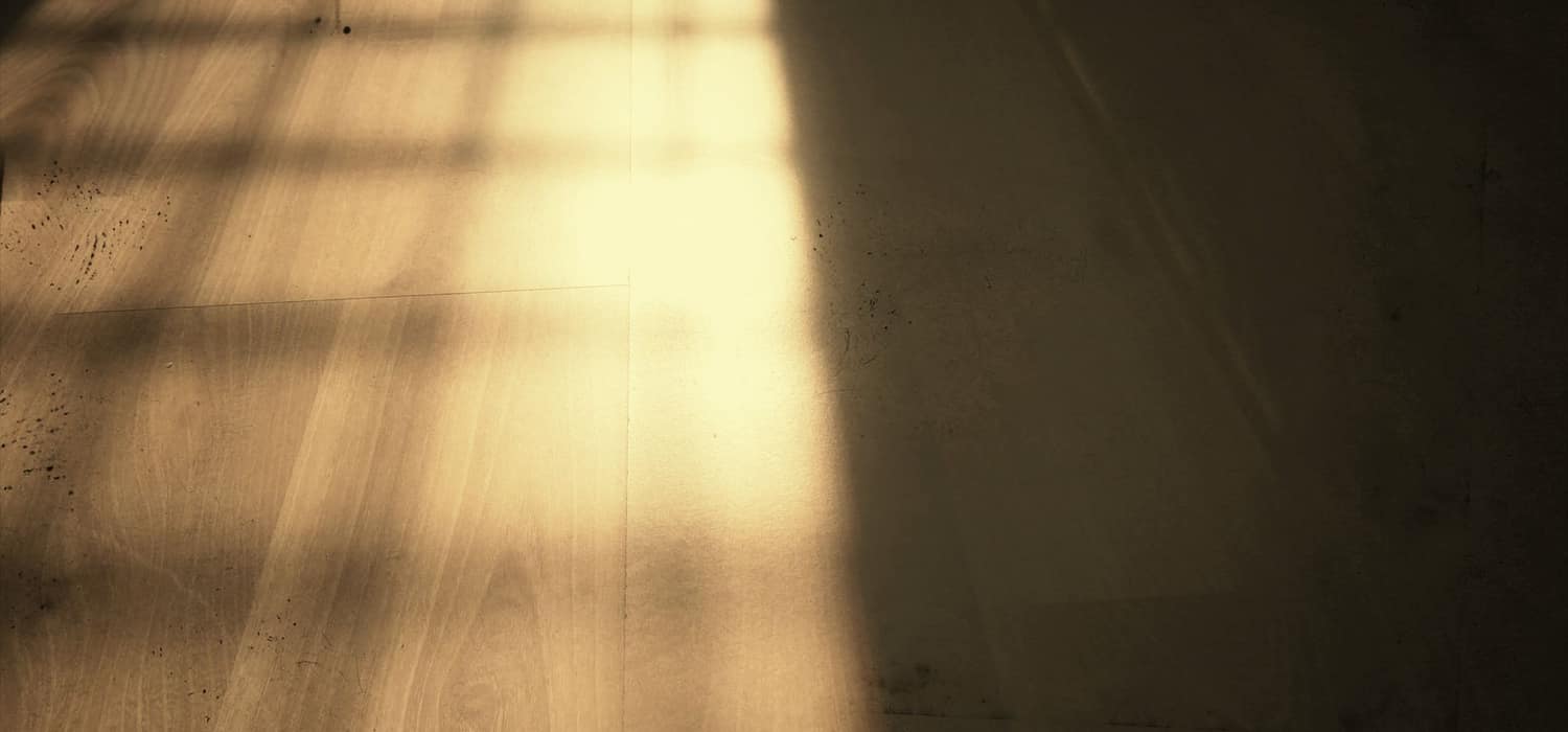 Warmes Fensterlicht liegt schräg auf einem Holzboden. Beispielfoto.